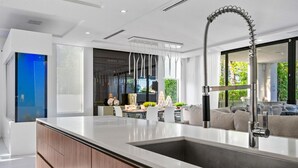 Uma cozinha moderna com uma ilha grande, eletrodomésticos de aço inoxidável e vista para a sala de estar.