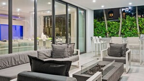 A modern outdoor living area with a sofa, chairs, and a fire pit. - Luxe Waterfront Villa with Private Pool (Fort Lauderdale)