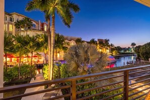 A hotel with a pool, palm trees, and a sunset view.