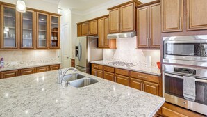 A kitchen with wooden cabinets, stainless steel appliances, and a marble countertop. - 8 Mi to the Galleria: Home w/ Balcony + Yard (Houston)