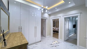 A spacious room with a marble floor, white wardrobe, and a wooden vanity. - Urban Sanctuary in the Heart of Dushanbe w/Stunning Views Steps from Rudaki Park (Dushanbe)