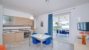Une cuisine moderne avec un coin repas, un téléviseur et une vue sur l’extérieur.