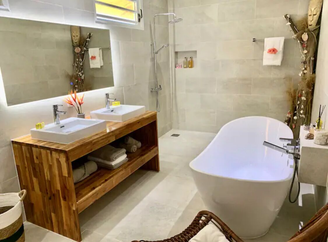 Een moderne badkamer met twee wasbakken, een vrijstaand bad en een houten wastafelmeubel.