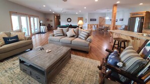 A spacious living room with a sofa, coffee table, and a pool table in the background.