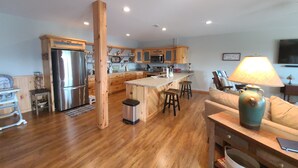 A modern kitchen with wooden cabinets, a stainless steel refrigerator, and a central island with stools.