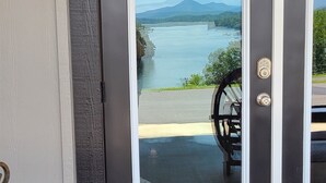 A dark brown door with a white frame, a metal gate, and a view of a lake and mountains through the glass.