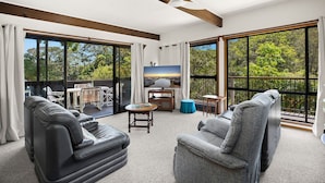 A spacious living area with a large balcony, leather sofas, a round coffee table, and a television.