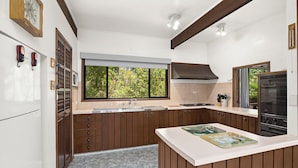 A modern kitchen with wooden cabinets, a built-in oven, and a window with a view of greenery.
