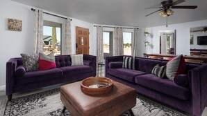 A living room with two purple sofas, a wooden coffee table, and a ceiling fan.