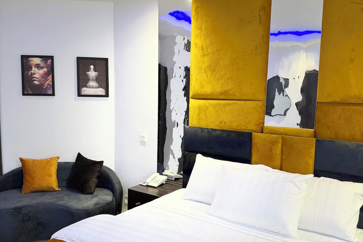 Une chambre d’hôtel moderne avec un grand lit, un canapé et une table de chevet avec un téléphone.