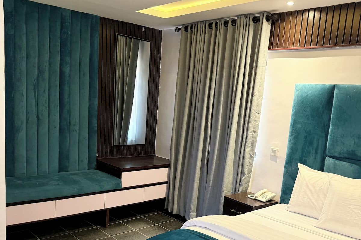 Une chambre moderne dotée d’un grand lit, d’un coin salon et d’une coiffeuse avec un miroir.