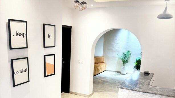 Un interior moderno con una recepción, citas motivacionales enmarcadas en la pared y vistas a una zona de estar acogedora.