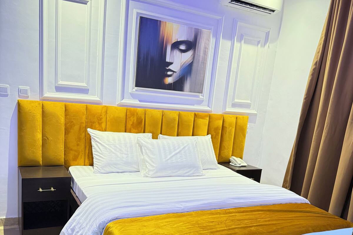 Une chambre moderne avec un lit, des tables de chevet, un tableau et un appareil de climatisation.