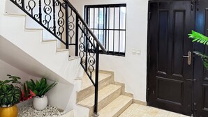 Una escalera con barandillas negras, una puerta negra y una lámpara en el techo.