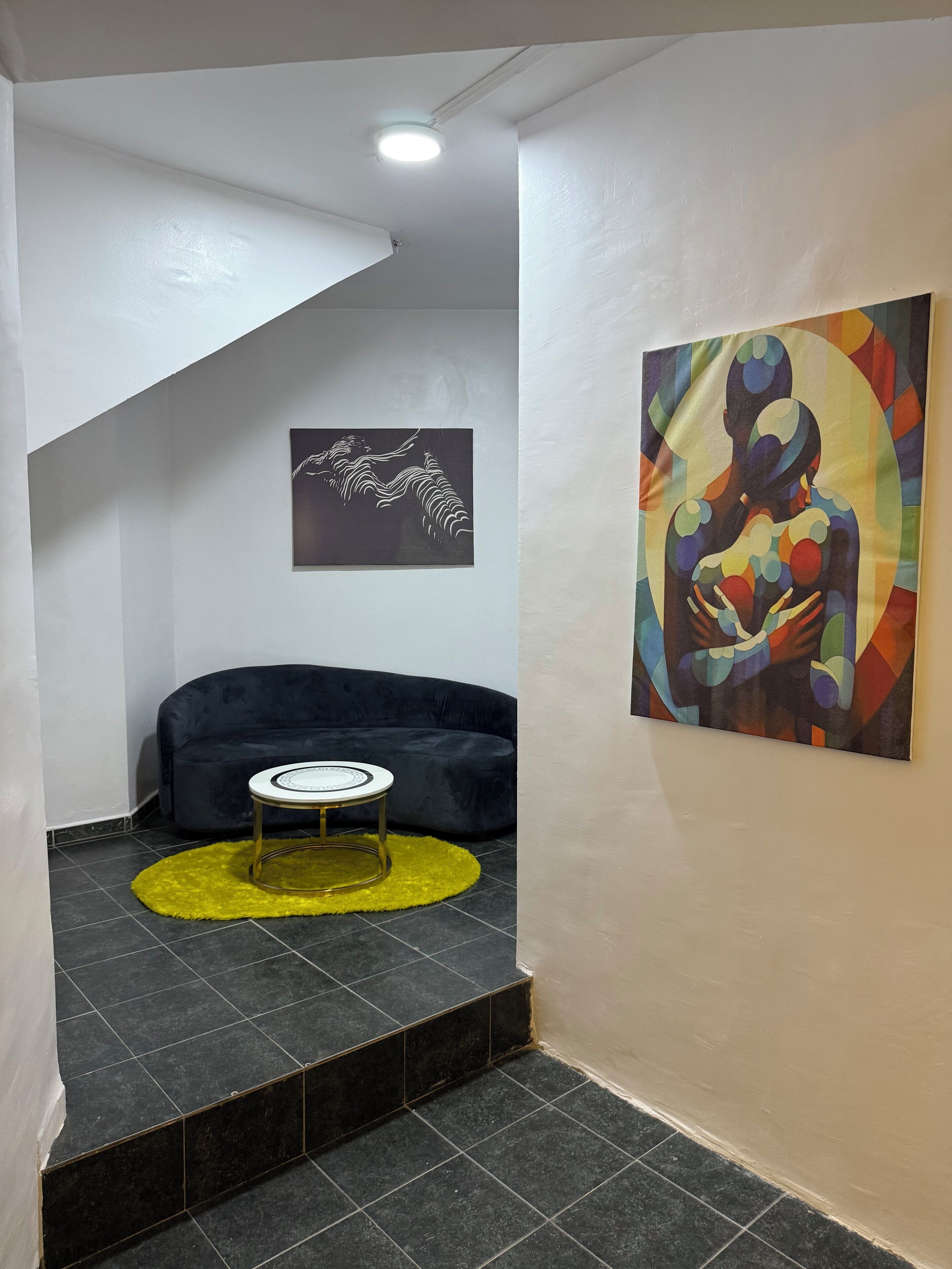 A modern interior with a dark sofa, a small round table, and two artworks on the walls.