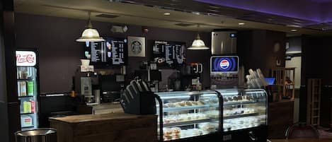 Een restaurant met een bedieningsbalie, menuborden, een Pepsi-koelkast en een koffieapparaat.