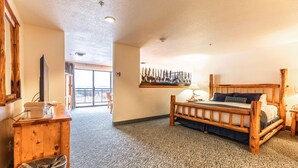 Una habitación amplia con una cama grande, muebles de madera, un cuadro en la pared y vistas por la puerta.