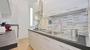 Una cocina moderna con estufa a gas, pileta de acero inoxidable y salpicadero de azulejos.