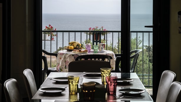Una mesa de comedor dispuesta para dos personas con vistas al mar.