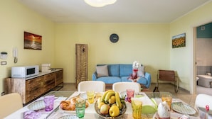 Un comedor con una mesa dispuesta para una comida, un sofá y un reloj en la pared.