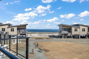 Une propriété située sur la côte, comprenant deux bâtiments modernes, un espace extérieur aménagé et couvert, et offrant une vue sur la mer.