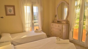 A hotel room with two beds, a dresser, a mirror, and a window with curtains. - Anacasa Tamarindo Oliva Nova Golf AP1001 (Oliva)