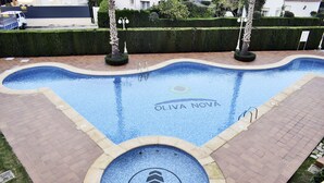 A swimming pool with a CHG logo, surrounded by a brick pathway and trimmed hedges. - Anacasa Tamarindo Oliva Nova Golf AP1001 (Oliva)