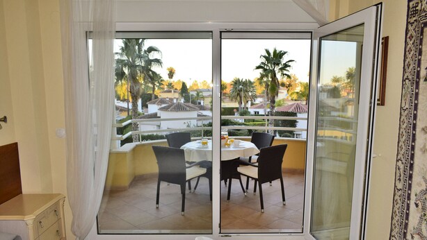 A hotel room with a balcony, a bed, a small table, and chairs. - Anacasa Tamarindo Oliva Nova Golf AP1001 (Oliva)
