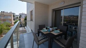 A balcony with a table set for dining, a sliding glass door, and a view of neighboring buildings.