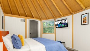 Quarto com cama, televisão na parede e janela.