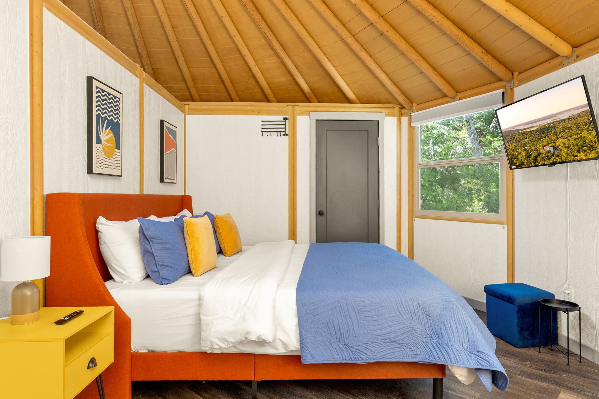 A bedroom with a bed, a nightstand, a TV, and a window.