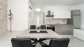Une cuisine moderne dotée d’un îlot central, de meubles blancs et d’un réfrigérateur en acier inoxydable.