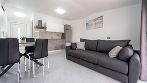Un salon moderne avec un canapé gris, des chaises noires et une table à manger.