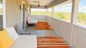 Un porche techado con una cama, una silla y vistas al exterior.