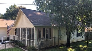 Een gelijkvloers huis met een veranda, een klein omheind gazon en een Amerikaanse vlag.