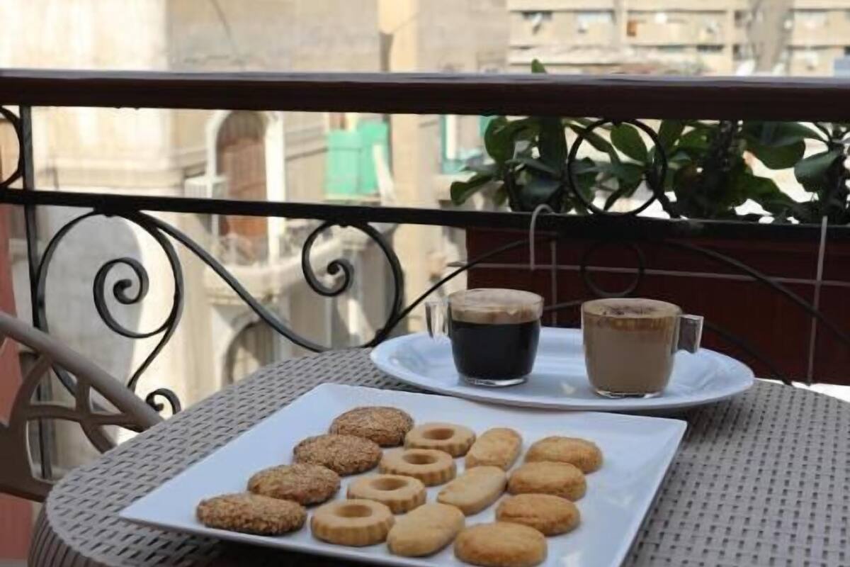 Ein Balkon mit einem für ein Frühstück gedeckten Tisch, inklusive Kekse und zwei Tassen Kaffee.