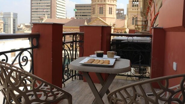 A balcony with a table set for two, featuring a plate of cookies and a cup of coffee. - Mid Downtown Hotel (Cairo)