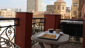 A balcony with a table set for breakfast, including pastries and coffee, overlooking a cityscape with historic buildings. - Mid Downtown Hotel (Cairo)