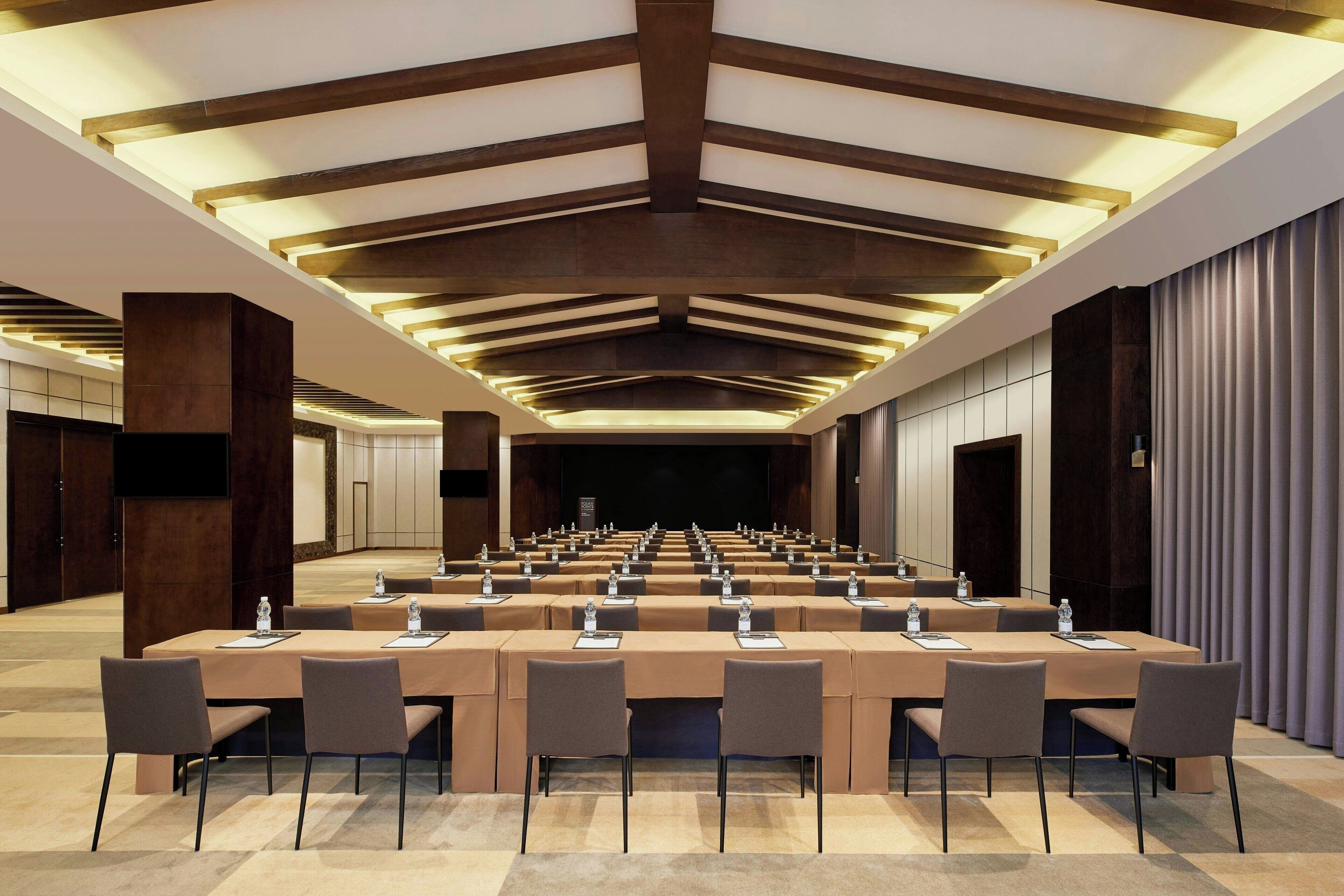 A conference room with multiple tables, chairs, and a large screen.