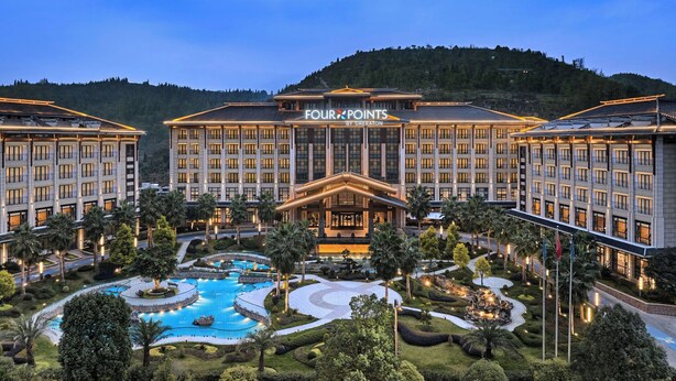 A hotel with a large pool, surrounded by well-maintained gardens and palm trees. - Four Points By Sheraton Anshun, Huangguoshu (Anshun)