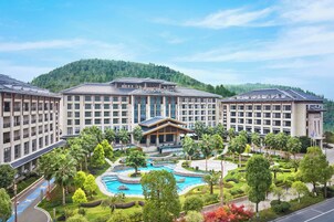 Un hotel con varias edificaciones, un área de piscina central y abundante vegetación.