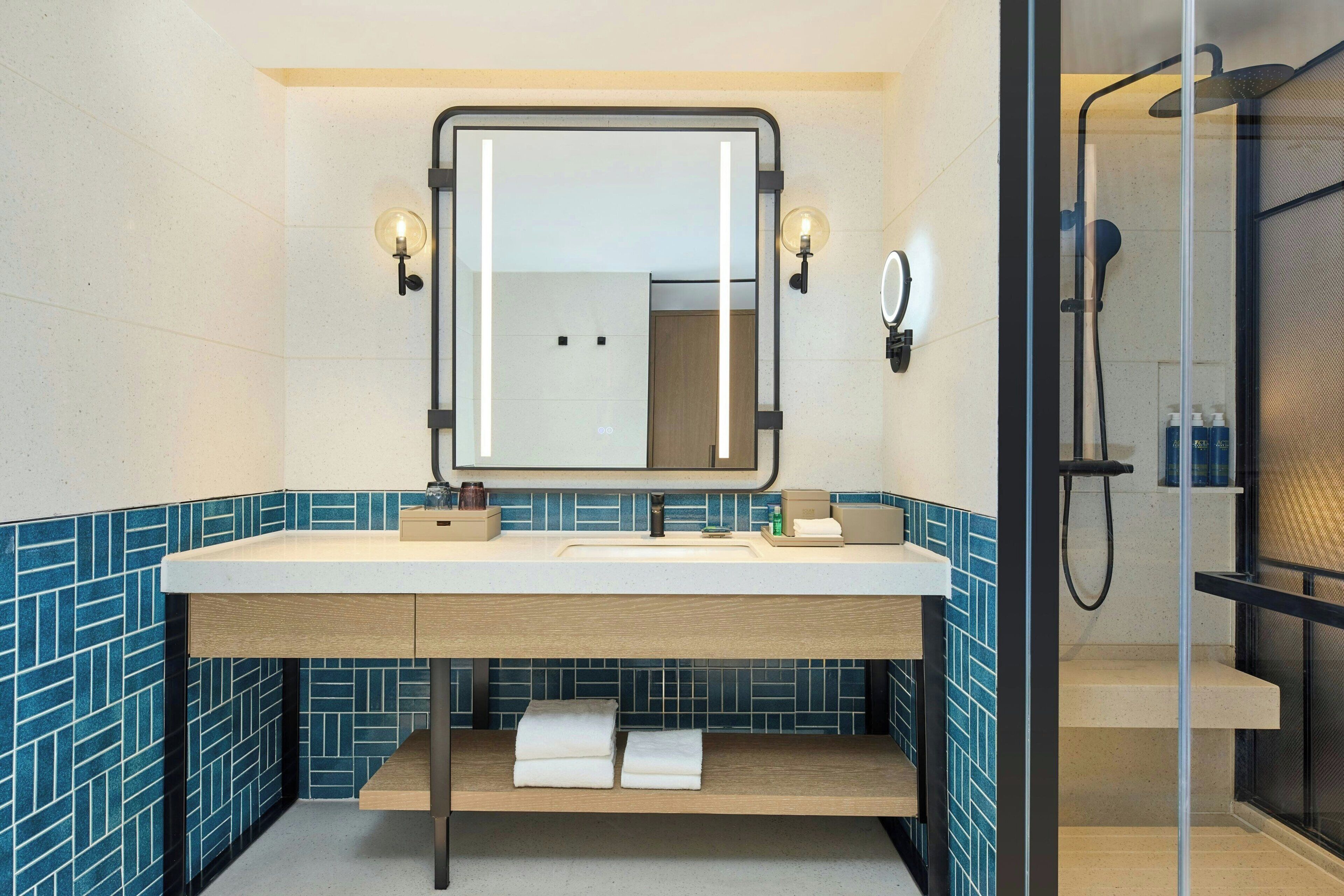 A modern bathroom with a large mirror, a sink with a countertop, and a shower area.