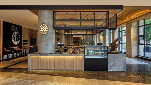 A modern lobby with a central reception desk, seating area, and a bar. - Four Points By Sheraton Anshun, Huangguoshu (Anshun)