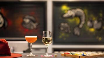 A bar area with two glasses of different beverages, a red hat, and a board game.