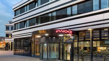 A modern building with a glass entrance and a neon sign reading "Moxy".