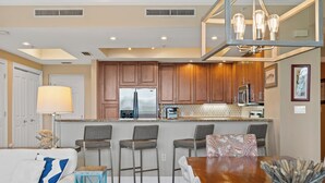 Eine moderne Küche mit Holzschränken, einem Edelstahlk ühlschrank und einer Bar mit Barhocker.