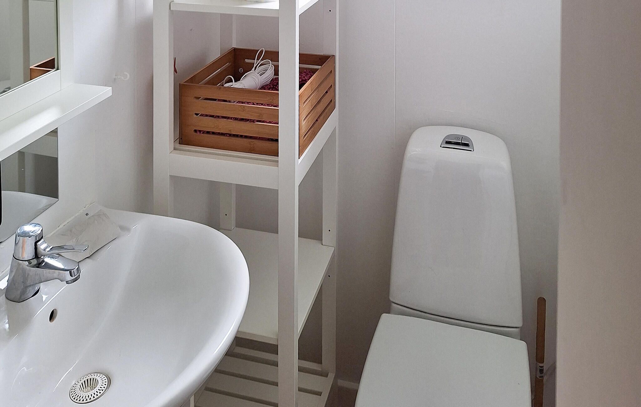 Ein Badezimmer mit Waschbecken, Spiegel und Holzregalen mit Kisten.