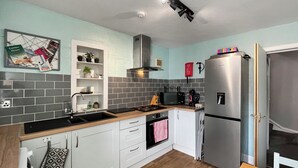 Cocina compacta con armarios blancos, un refrigerador de acero inoxidable, un microondas y una estufa.
