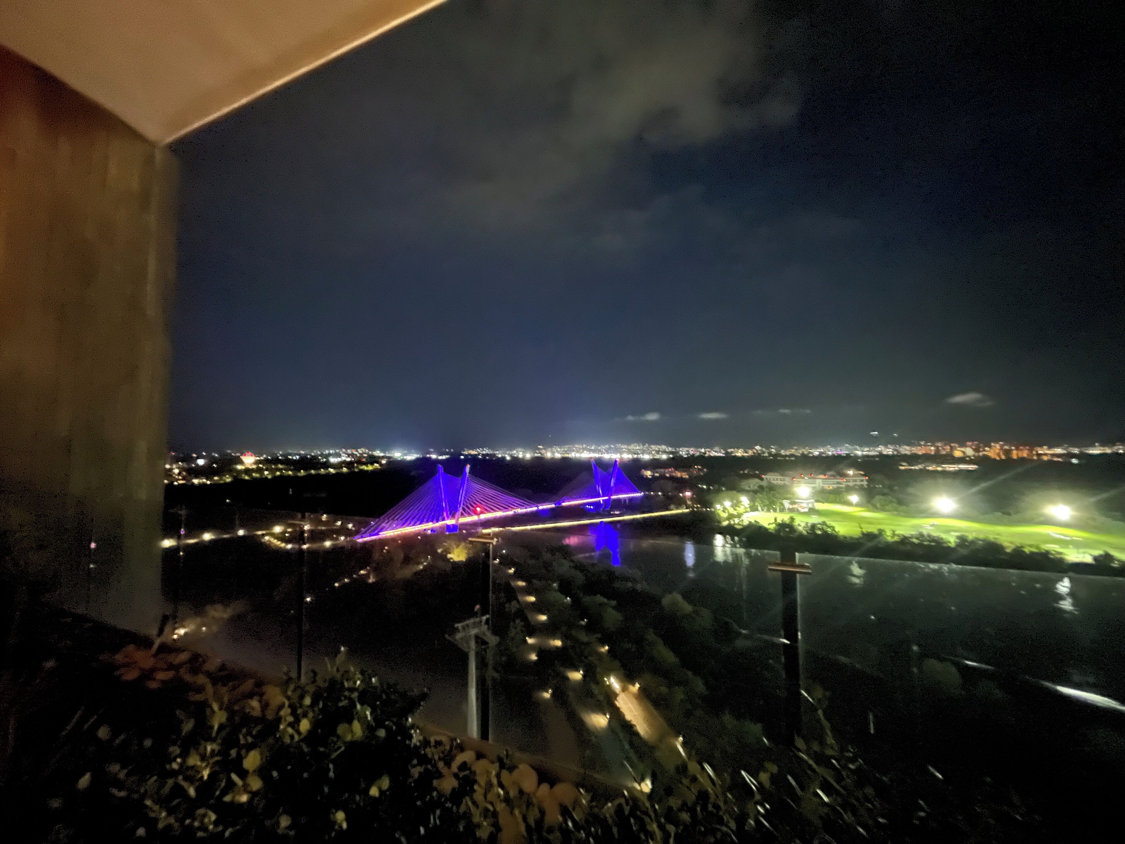 Une vue nocturne d’une ville, avec un pont illuminé et une rivière.