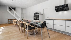 Une cuisine moderne avec un coin repas, des chaises en bois, un four encastré et un escalier.